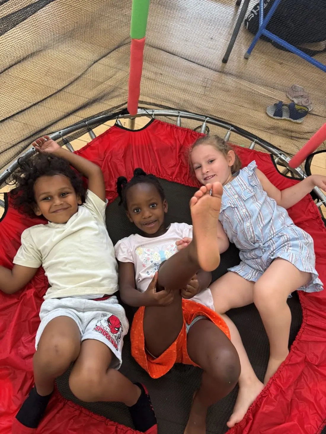Three children lying on a trampoline laughing at the end of the day